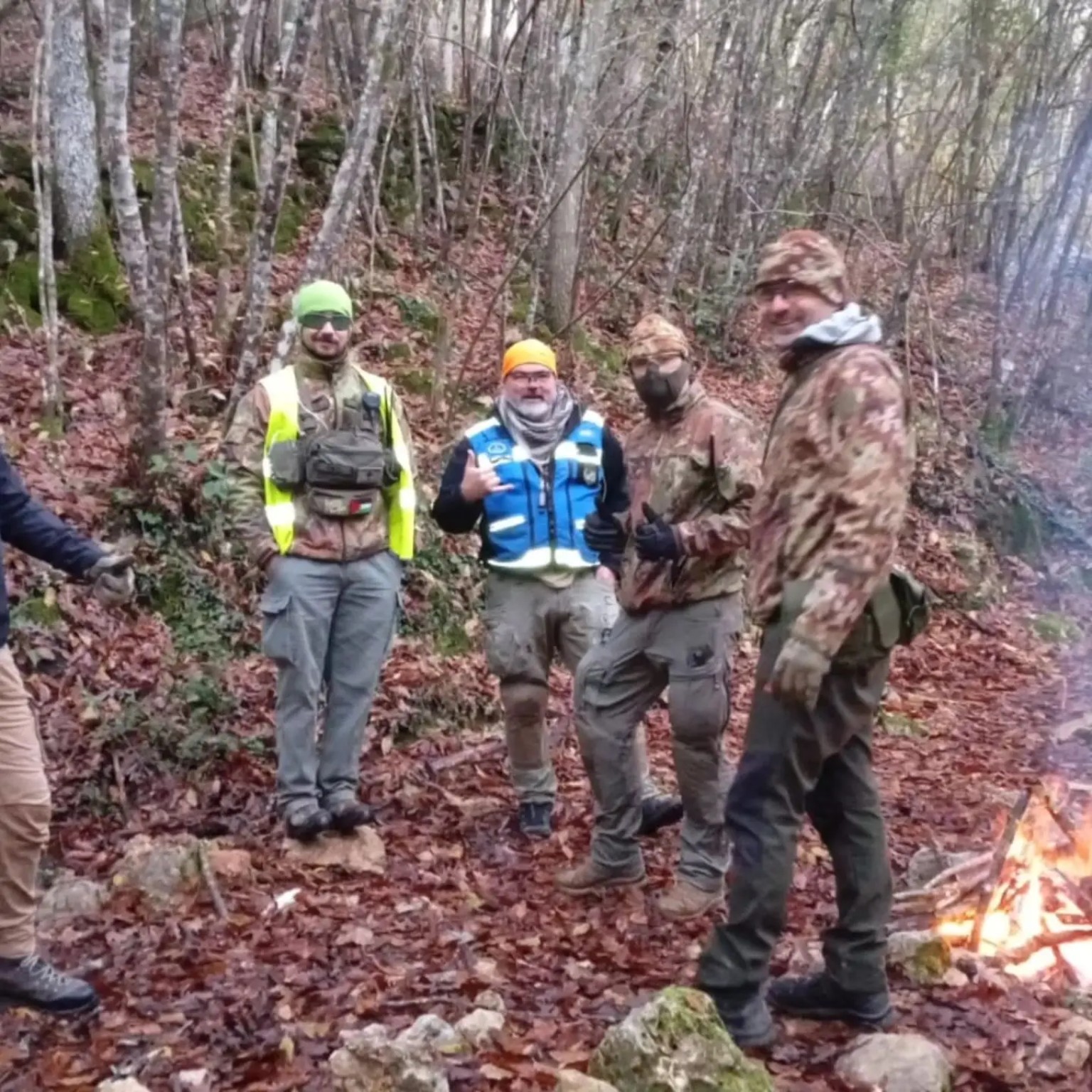 Giocatori e addetti al campo riuniti nel bosco accanto a un piccolo fuoco